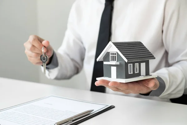 stock image Home insurance agent holding a house model and a key in the office. home loan insurance concept.
