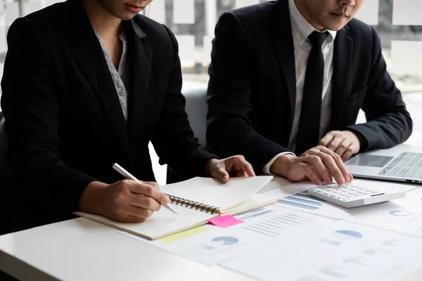 stock image Two businessmen are analyzing earnings on a graph to plan investments in the office room. business discussing and planning strategy concept.