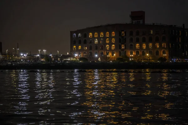 赤いフックの古い桟橋の建物は夜灯と水 ブルックリン ニューヨークで反射します ストック画像