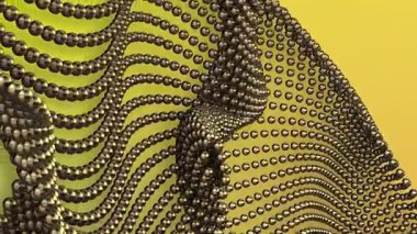 Birbirine bağlı altın boncukların dalgalı iplikleri, açık yeşil bir zemin üzerinde akan, rastgele boncuklara dönüşür..