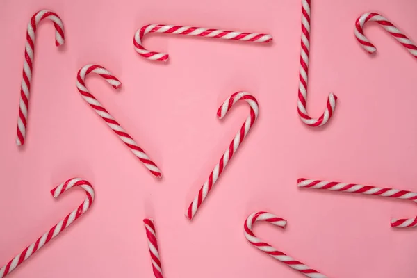 Candy canes on light pink background. Red and white striped hard candy cane. Candy shop concept. Merry Christmas decoration.