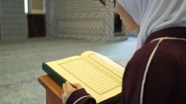 Müslüman Kız Kuran 'a Dua Ediyor, camide Kur' an 'dan namaz kılan bir kızın görüntüsü, ibadet ve namazın İslami biçimleri, kitaplarda okuması. 