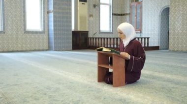 Rahle 'de Kur' an Oku, Asyalı Müslüman kız diz çöküp camide Kuran okuyor, Müslümanlar İslam 'a tapıyor.