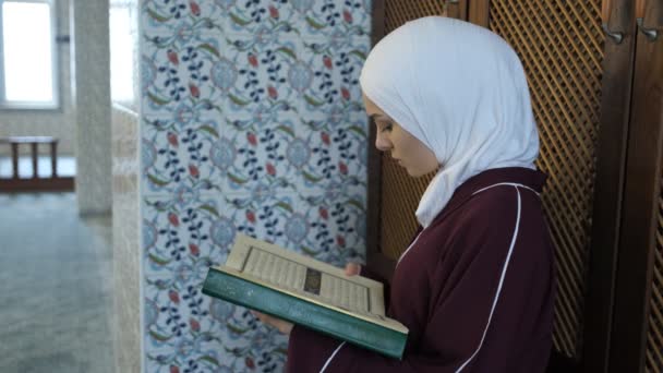 在清真寺里 穆斯林女孩手里拿着圣书祈祷 念着清真寺里的古兰经 用阿拉伯字母背诵着神圣的宗教书籍 — 图库视频影像