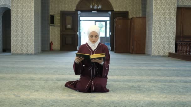 Hijabi妇女祈祷清真寺 年轻女孩坐在地板上读经 在清真寺祈祷 是Hijab妇女的祈祷 — 图库视频影像