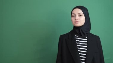 Başörtülü kız sağ tarafa bakıyor yeşil ekran, kız krom anahtarın önünde yön gösteriyor, genç insan ifadesi gülümsüyor