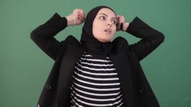 Müslüman kadın sinirlenir ve sıkılır, krom anahtarın önündeki kızgın kız, genç adam deli, negatif enerji, izole edilmiş yeşil arka plan
