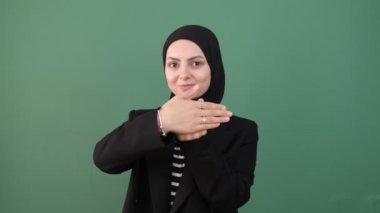 Müslüman kadın parmağı göster, parmağın hediye olsun, tesettürlü genç kız izole edilmiş yeşil arka plan işaret parmağı, genç bayan gülümsemesi 
