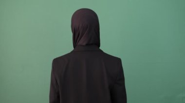 İzole edilmiş yeşil arka planda gülümseyen, gülümseyen bir kızı işaret ediyor. Mutlu genç insan ifadesi.