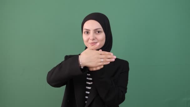 イスラム教徒の女性の指を表示 あなたの指に贈り物 孤立した緑の背景の看板の指の前で若い女の子のヒジャーブ 若い女性の表情の笑顔 — ストック動画