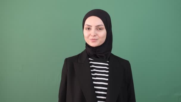 女性穆斯林做得很好 一切都很好 积极的女孩在孤独的绿色背景的女孩面前 头巾人的脸上挂着微笑 — 图库视频影像