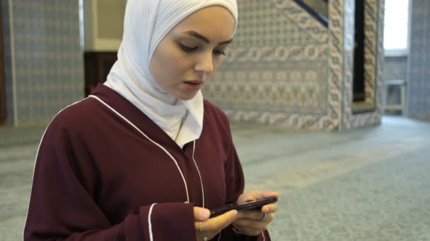 画面上で祈る女性 クルアーン朗読オンラインプラットフォーム モスク内で祈るアジアのイスラム教徒の女の子 モスク内の電話を使用して — ストック動画