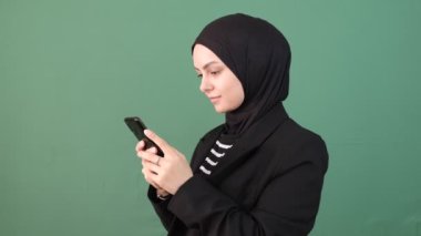 Müslüman kadın mesaj telefonu, kız gülümsemesi kroma tuşunun önünde, tesettürlü genç işaret akıllı telefon ekranı