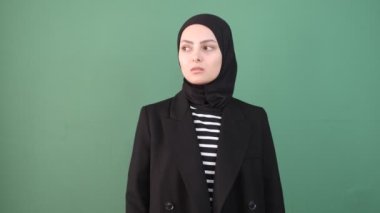 Müslüman kadın üzgün, siyah elbiseli Müslüman kız yeşil ekranın önünde kendine sarılıyor, genç adam mutsuz, kız kötü hissediyor, ifade üzgün.