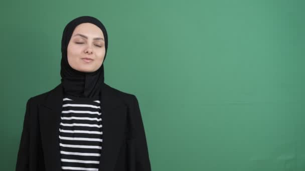 左を示すイスラム教徒の女性 緑の画面の前に方向を示す若いヒジャーブ人 すべてが肯定的です 表情笑顔女性 — ストック動画