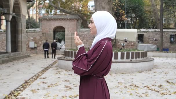 年轻女孩祈祷庭院 伊斯兰崇拜和旅游目的地 在清真寺的院子里举手祈祷的高加索女孩形象 — 图库视频影像