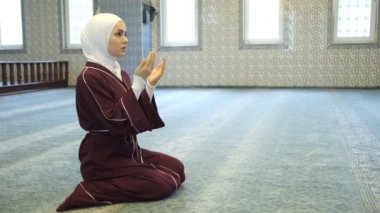 Camide ibadet, mavi halıda kırmızı bir pelerinle dua eden baş kız, af dileyen genç kız.