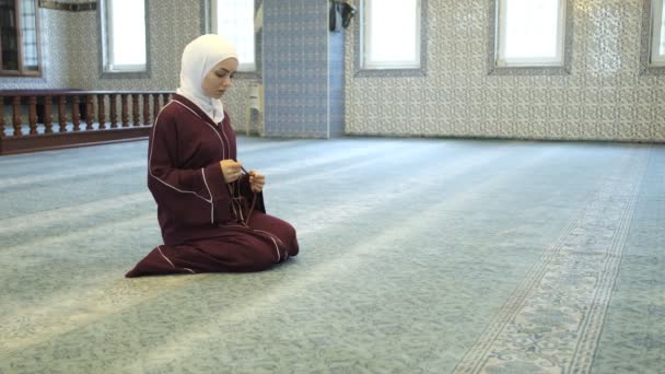 白人の少女ロザリー伯爵 指一本で数えるビーズ イスラム教の崇拝 モスクでロザリオと祈る — ストック動画