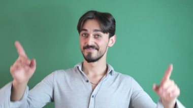 Yeşil ekranın önündeki gri tişörtlü neşeli, hevesli, aktif, İspanyol sakallı adamı işaret eden bu adam...