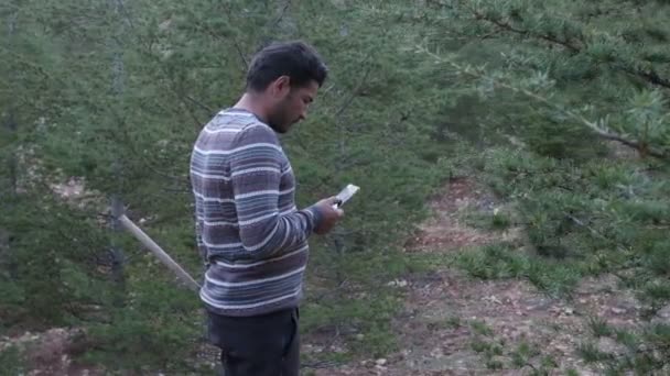 Een Jongeman Loopt Door Het Bos Met Een Telefoon Kijkt — Stockvideo