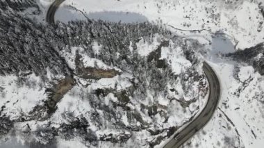 Karlı ormanın kışın karayolu geçişinden en üst manzarası, karla kaplı yollar ormanın içinden geçer Aralık ayında dağlar geçer, kış soğuktur.