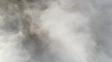 Yeryüzü beyaz bulutların altında ve mavi gökyüzü gökyüzünden, bulutlu hava yerleşim alanlarını ve tarlaları kaplıyor.