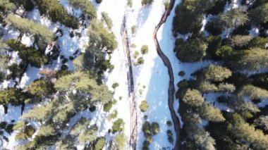 Kış ormanlarında karlı kıyılar akan bir nehir dağlar ve güneşli gökyüzü ve arka planda birçok gök gürültüsü, insansız hava aracı manzarası