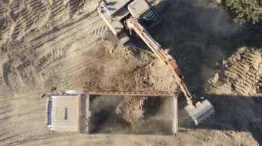 Kum ocağında çalışan kazıcı ve kamyon, kazıcı bir çöp kamyonuna kum yüklüyor, bahçenin yanında çalışan inşaat makineleri, insansız hava aracı.