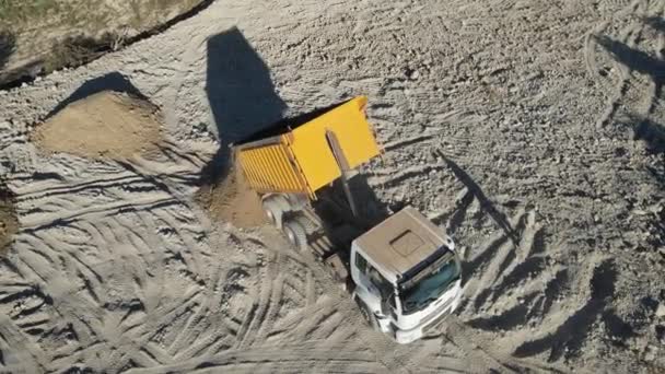 一辆垃圾车在建筑工地卸下沙子 空中看到站在卡车前面的人都是泥土 — 图库视频影像