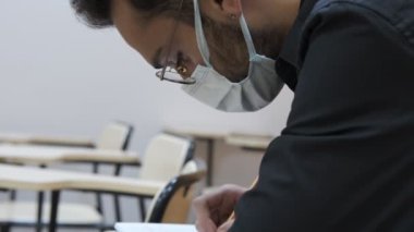 Öğrenci Maskesi Sınav Sınıfı, salgınla ilgili bir sınava girmek, dersten notlar almak, çalışkan öğrenci imajı ve maske takmak.
