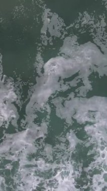 Mavi enerjinin ve berrak okyanus suyunun canlılığı. Yukarıdan aşağıya insansız hava aracı perspektifinde güçlü fırtınalı deniz dalgaları. Köpüklü beyaz dokusuyla denizdeki çarpan dalga çizgisi.