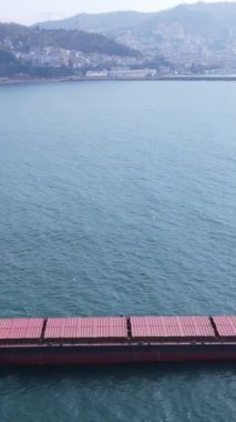 Drone view of the red cargo ship passing through Giresun offshore, merchant ship in the black sea passing near the shore