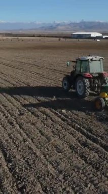 Traktörün tarlayı sürttüğü hava aracı görüntüsü, tarım arazilerinde traktörle çalışması, traktörün çapaladığı toprağın tozu bırakması.