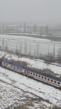 Hava aracı görüntüleri, doğu ekspresinin sisli havada ağaçların arasından geçişini gösteriyor. Yolcu taşımacılığı treni karla kaplı demiryolu hattıyla ilerliyor.