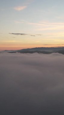 İnsansız hava aracının sağdan uçuşu bulutlu ve öğleden sonra güneşli bir dağla güneşin doğuşunu görmek için. Ormandaki doğa harikaları.