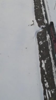 Karla kaplı raylarda giden trenin görüntüsü İHA tarafından çekilen çekim, kışın kargo taşıyan lokomotif, karlı yollardan geçen yük treni manzarası