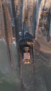 Buldozer kıyıya kum taşıyor, buldozer kıyıya kum taşıyor ve insanlar önlem almadan etrafta dolaşıyor.