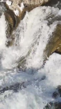 The image of the water flowing through the rocks, the flow of the water falling from the stones, the flow of the water from the waterfall