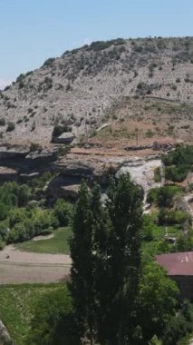 Çimenlikte eski bir köy Ve engebeli bir vadinin tepelerinde seyrek ağaçlar