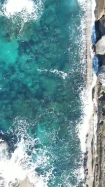 Drone view of the crystal clear sea waters of Kyrenia, turquoise color of the open sea, rocks and the natural beauty of cyprus with waves crashing on the beach