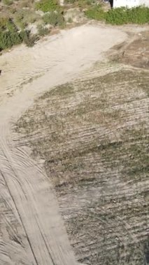 Kazıcının evlerle bahçeler arasındaki toprak alanındaki konteynırlara kum yüklediği hava görüntüsü, kazıcılar köyler arasında toprak yüklüyor