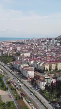 Aerial drone view of the coastal city of Trabzon, the city located on the coastline, the blocks of apartments facing the sea, mountains behind it and the city overlooking the black sea