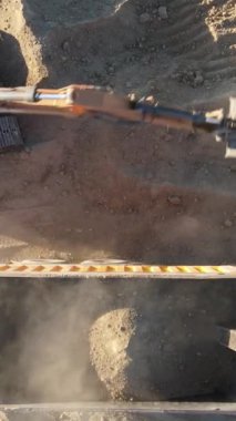 Kazıcının topraktan kamyona kum taşıdığı hava görüntüsü, topraklanmış kazıcı kamyonları yüklüyor, kazıcı bir çöp kamyonuna kum yüklüyor.