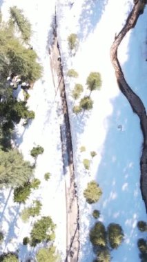 Kış ormanlarında karlı kıyılar akan bir nehir dağlar ve güneşli gökyüzü ve arka planda birçok gök gürültüsü, insansız hava aracı manzarası