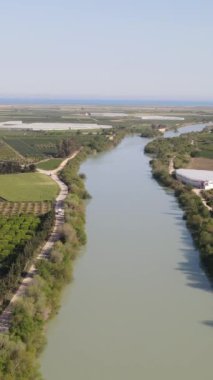Nehir kenarındaki tarlaların hava manzarası, Göksu deltasındaki tarlaların insansız hava aracı görüntüsü, içinden akan geniş yeşil arazi ve su.