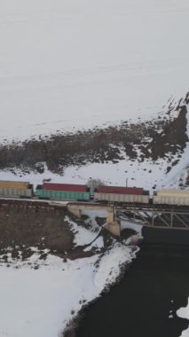 Karlı bir kış gününde, yük treninin hava görüntüsü köprüyü geçer, İHA uzun vagon yük treni teslimatı yapar. 