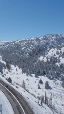 Karla kaplı dağın içinden geçen otobanın insansız hava aracı görüntüsü, kışın ulaşımın devam ettiği ana yollar.