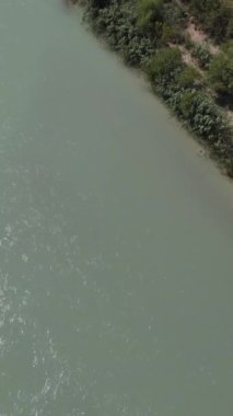 Nehir kıyısı doğası, dere yatağında su akışı, nehrin etrafındaki tarım alanları, yeşillik tarım arazisinde akış.