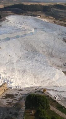 Drone view of Pamukkale travertines, natural beauty consisting of waterfalls and swimming pool with white minerals in Turkey, white travertines on one side of the mountain