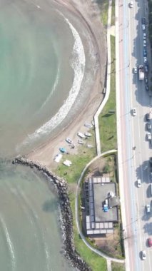 Drone view of seaside city Ordu over sea, waves crashing on shore, public park on coastal road, Ordu city settlement